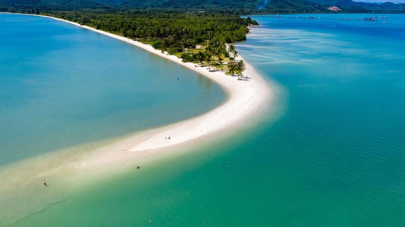 Длинная изогнутая песчаная коса уходит в бирюзовое море, вид с высоты