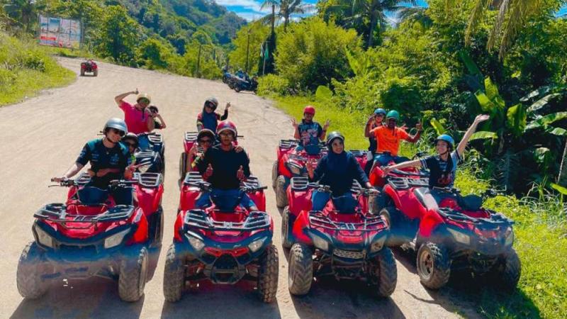 Группа на красных квадроциклах машет в камеру на дороге в холмах над Катой