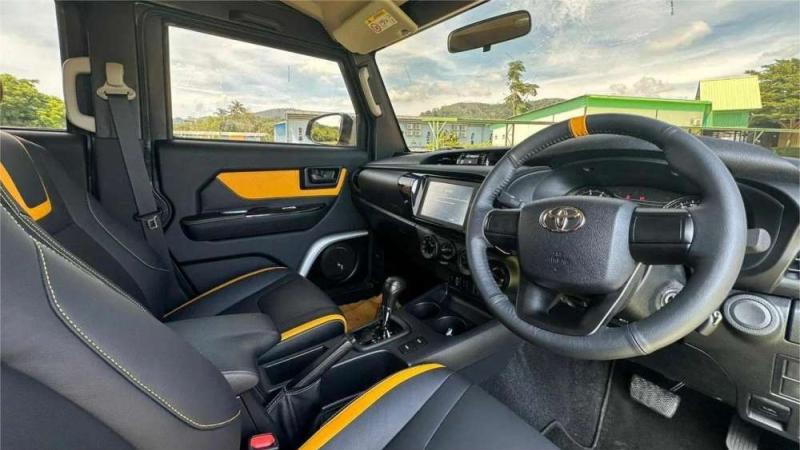 Салон внедорожника Toyota: чёрные сиденья с жёлтыми акцентами, за стеклом тропические деревья