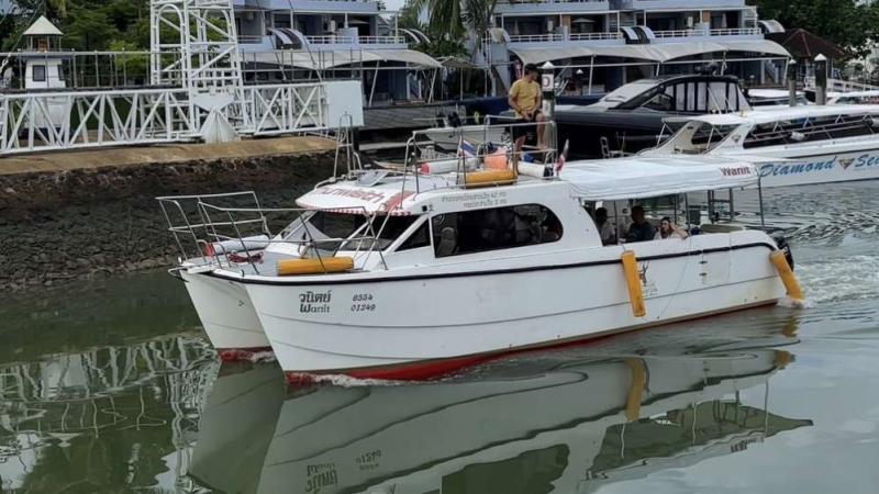 Два белых катера у причала марины в спокойной воде, за ними пирс и дома