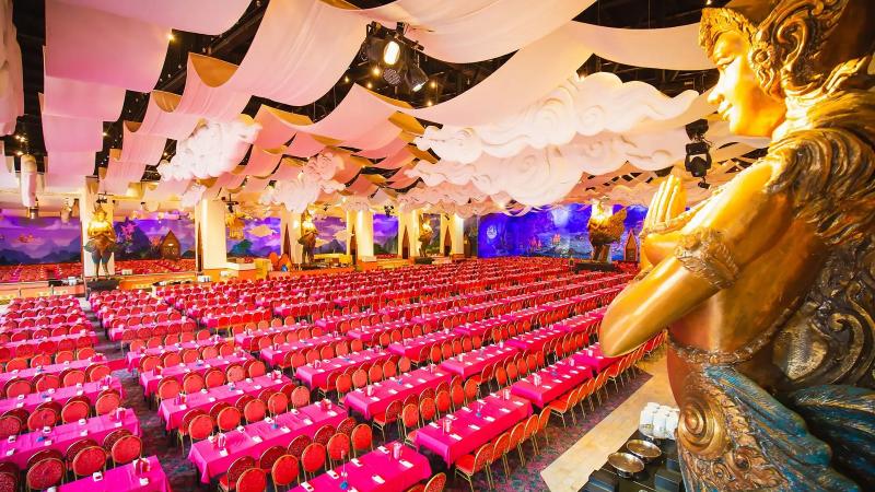 Зал ресторана Golden Kinnaree в парке Phuket FantaSea с рядами столов и золотой статуей киннари