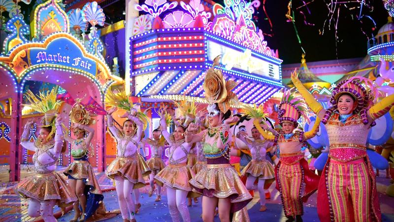 Уличный парад артистов в пёстрых костюмах на карнавальной ярмарке Carnival Magic