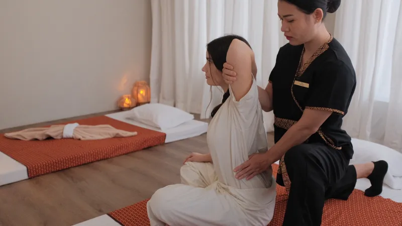 Тайский массаж в Nua Thai Massage: мастер в чёрной форме делает растяжку гостье в белой одежде