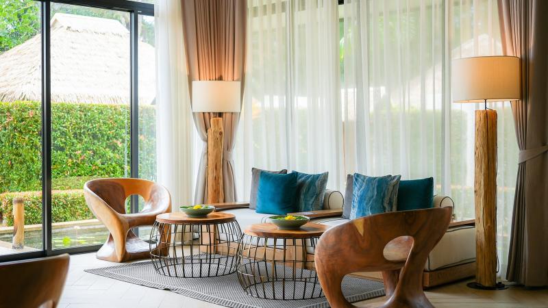 Лаунж салона Oasis Tropical Retreat: деревянные кресла, бирюзовые подушки, окна в сад