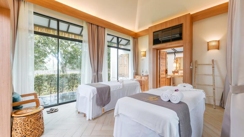 Два массажных стола в светлой вилле салона Tropical Retreat с большими окнами в сад
