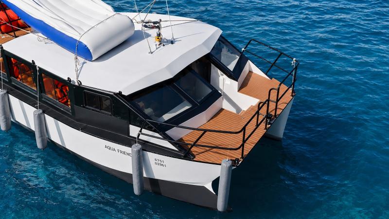 Нос катамарана Aqua Friend со сложенной горкой на крыше над бирюзовой водой