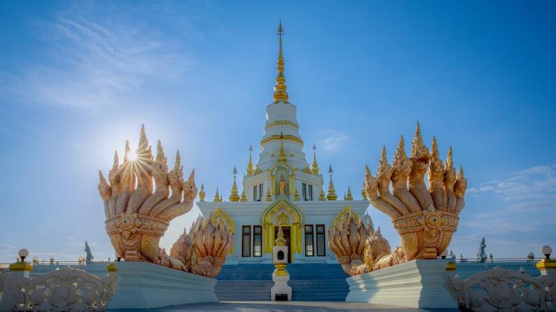 Белая чеди Phra Maha Chedi храма Ват Саен Сук и золотые многоглавые наги у лестницы