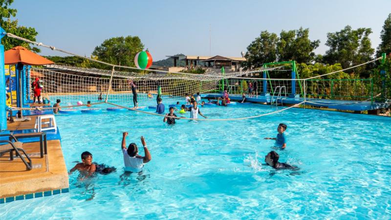 Гости играют в водный волейбол в бассейне аквапарка Рамаяна
