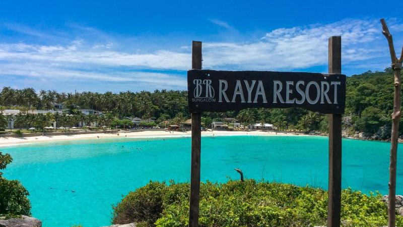 Табличка Raya Resort над бирюзовой бухтой с белым пляжем на острове Рача Яй