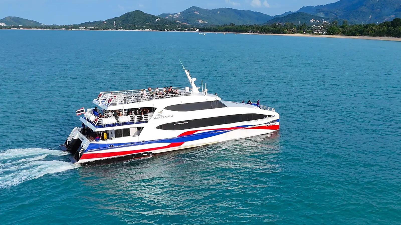 Скоростной катамаран Lomprayah идёт вдоль берега острова, пассажиры на открытой верхней палубе