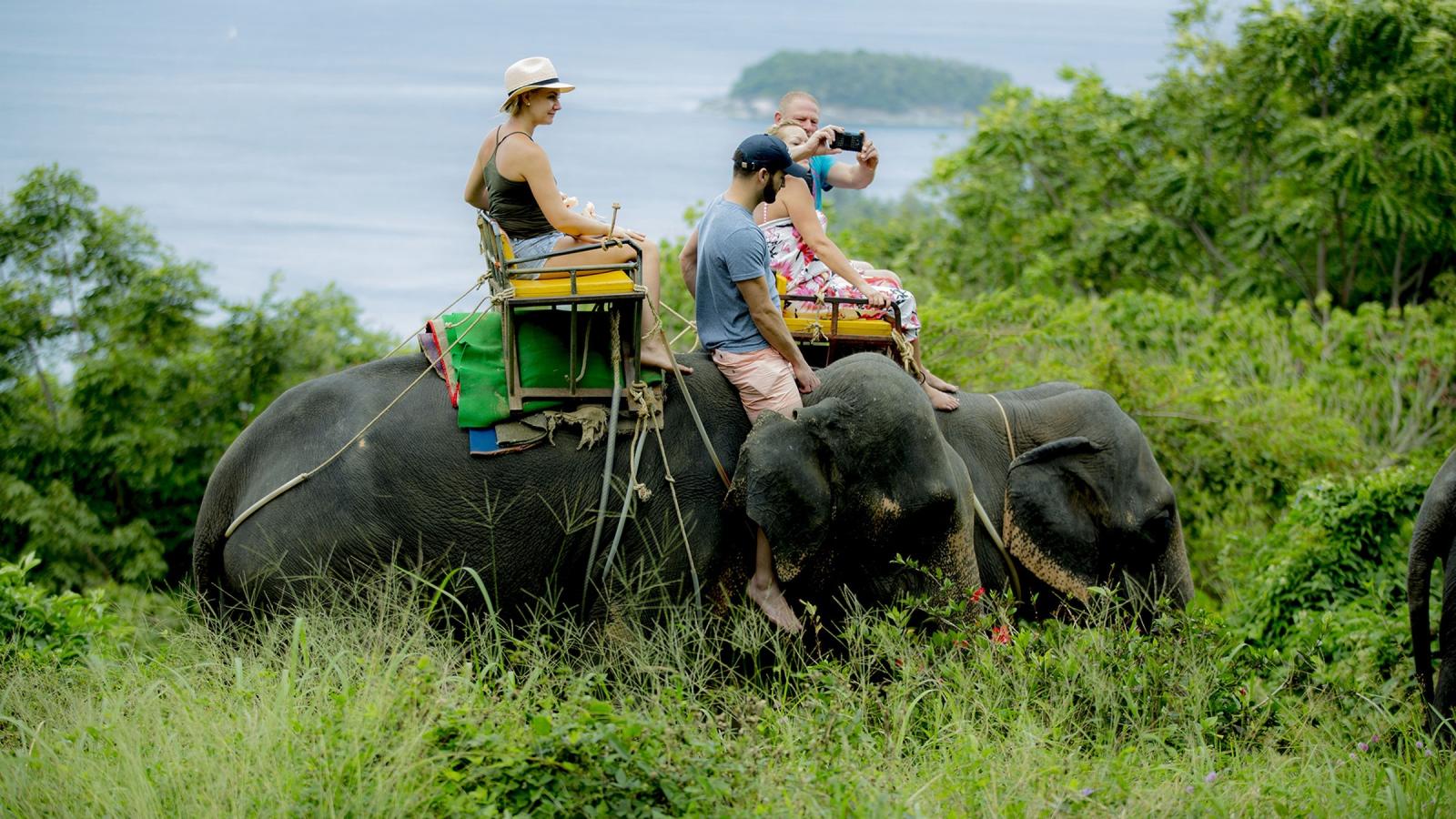 Катание на слонах на Пхукете: двое туристов на слоне на холме Kok Chang Safari, внизу море и остров