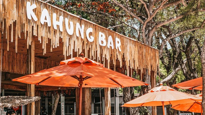 Kahung Bar на острове Корал: деревянная вывеска и оранжевые зонтики у пляжа