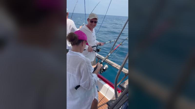 Гости рыбачат со спиннингами у борта лодки — троллинг на морской рыбалке на рассвете