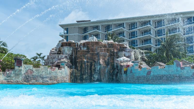 Бассейн аквапарка Splash Jungle на Пхукете у искусственных скал и стены-крепости, позади — корпус отеля