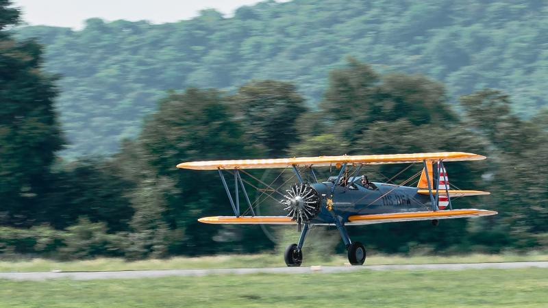 Биплан Stearman на взлёте с травяной полосы аэродрома