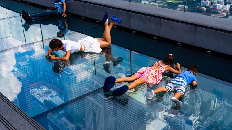 Дети и взрослые лежат на стеклянном полу SkyWalk на высоте 314 метров
