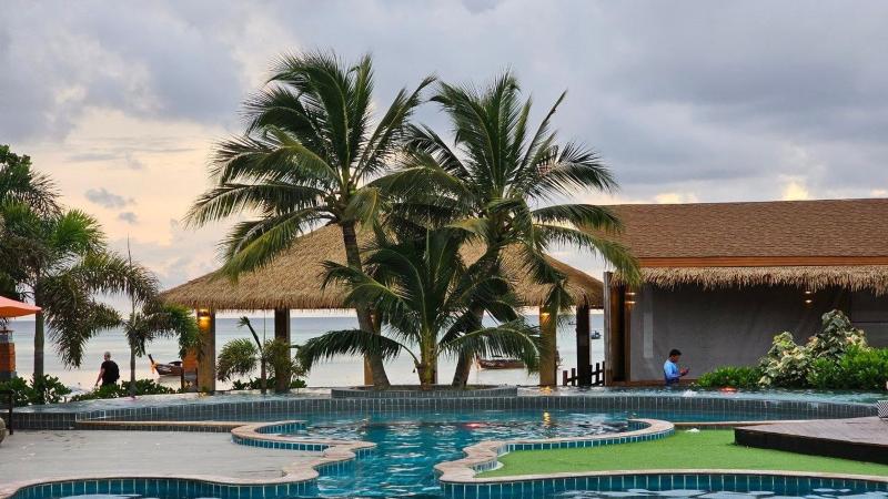 Бассейн отеля Andaman Beach Resort на Пхи-Пхи Дон: пальмы, павильон с соломенной крышей и море за ним