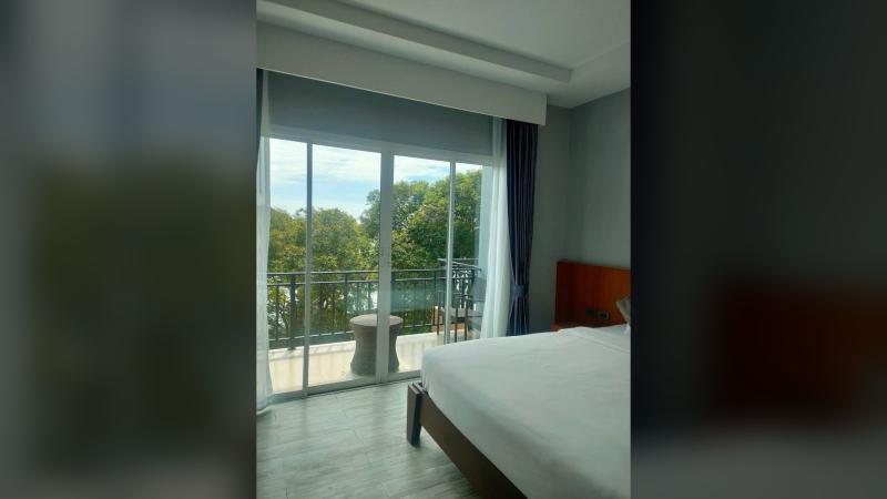 Номер отеля Andaman Beach Resort с выходом на балкон, за окном зелень и море