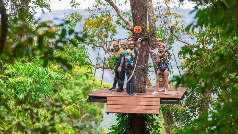 Группа с инструктором на платформе вокруг дерева, за лесом горы — зиплайн Patong Mountain View