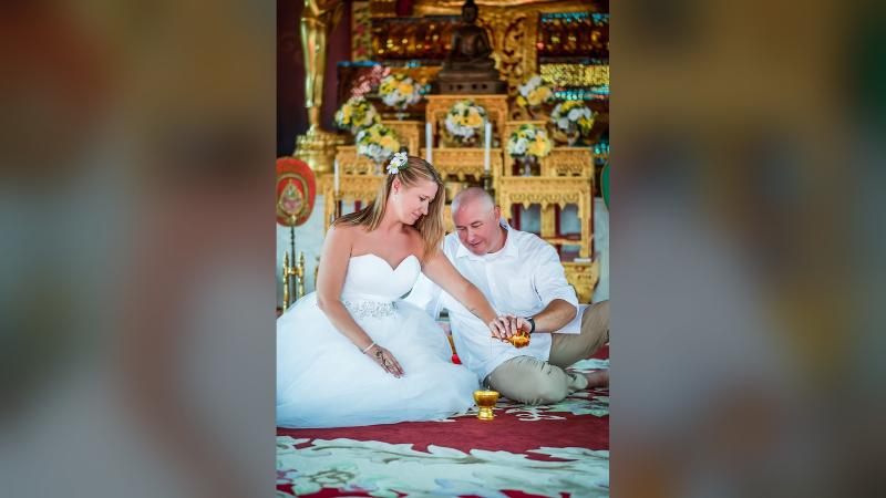 Невеста и жених сидят на ковре храма и льют воду в чашу — водный ритуал объединения