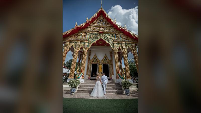 Жених и невеста у входа в храм с резным золотым фронтоном — свадебная фотосессия