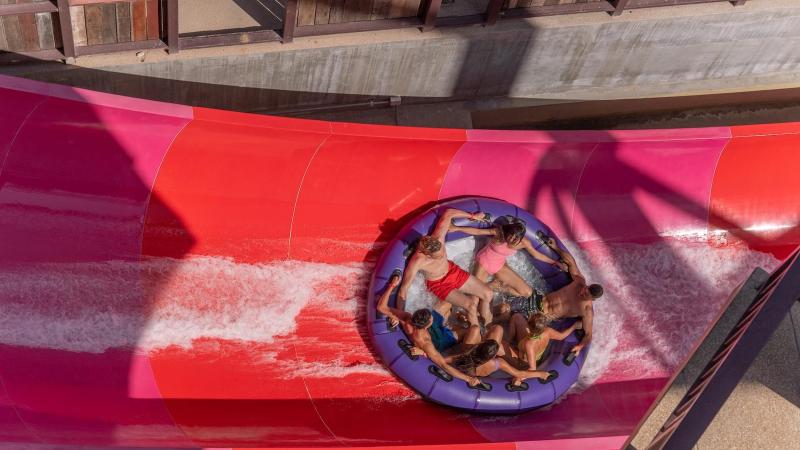 Компания на большом круглом плоту спускается по красной горке Rock'N'Raft в аквапарке Андаманда