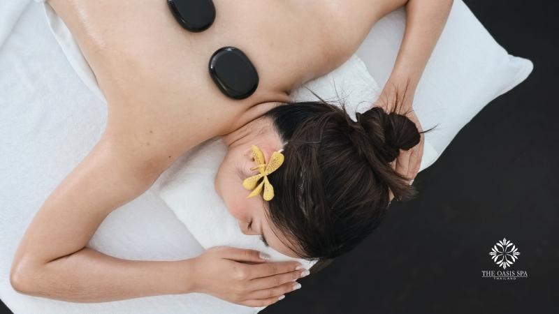 Массаж горячими камнями в Oasis Spa: гладкие камни на спине, цветок в волосах гостьи