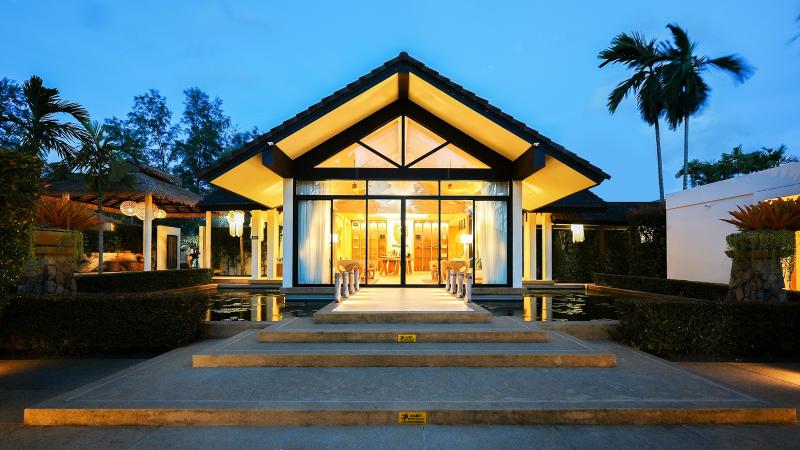 Вход в салон Oasis Tropical Retreat в Лагуне вечером: стеклянный павильон с подсветкой