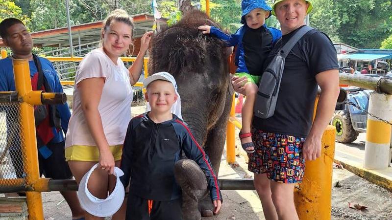 Семья фотографируется со слонёнком в лагере Seaview Elephant Care, малыша папа держит на руках