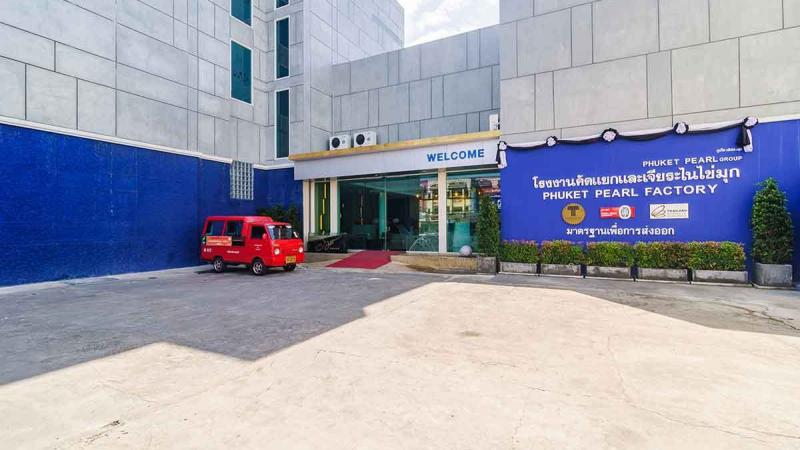 Вход в Phuket Pearl Factory на Пхукете: синяя вывеска и красный микроавтобус у здания