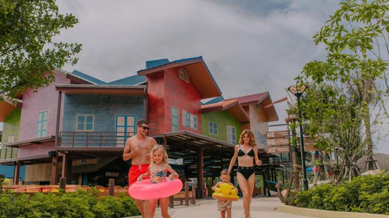 Семья с надувным кругом у разноцветных домиков Tropical Beach в аквапарке Андаманда