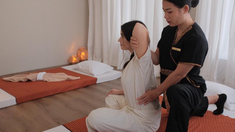 Тайский массаж в Nua Thai Massage: мастер в чёрной форме делает растяжку гостье в белой одежде
