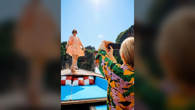 Туристки фотографируются на носу лонгтейла у скал залива Пханг Нга