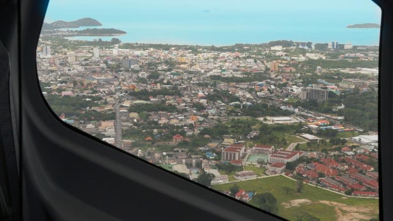 Город с красными крышами из окна вертолёта, вдали — море и острова